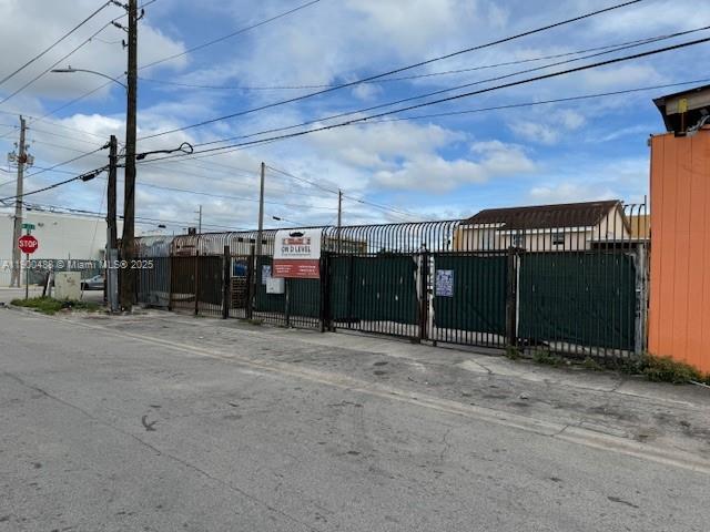 A fenced-in vacant lot with a sign sits along a paved street — 2484 NW 21st Ter, Miami FL 33142, MIAMI, FL