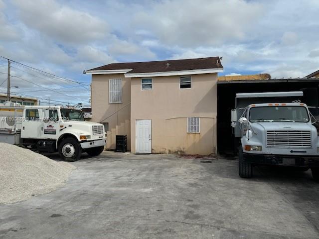A two-story beige building stands between two large white trucks in a paved lot — 2484 NW 21st Ter, Miami FL 33142, MIAMI, FL