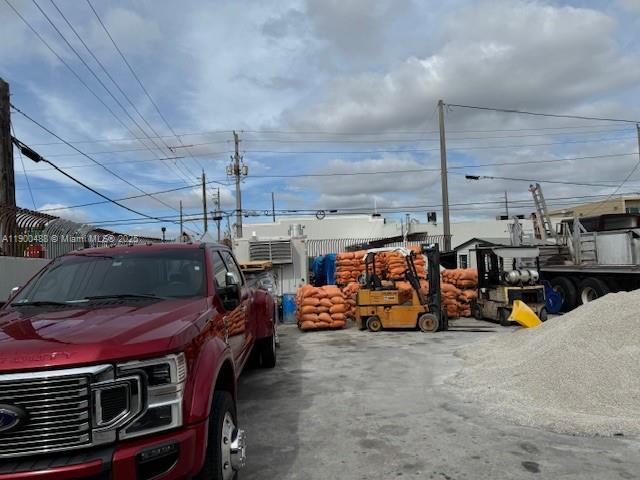 A red pickup truck is parked in a gravel lot next to a yellow forklift — 2484 NW 21st Ter, Miami FL 33142, MIAMI, FL