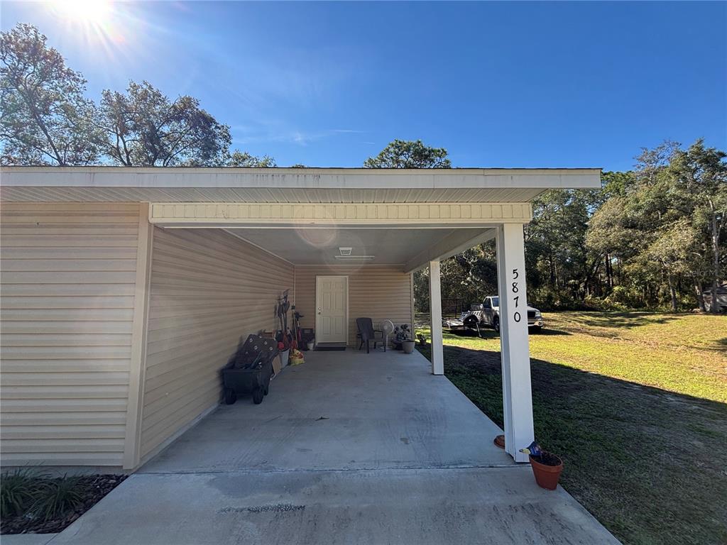 A concrete carport with a white support post and tan siding attached to a house — 5870 SE 171ST COURT, OCKLAWAHA, FL
