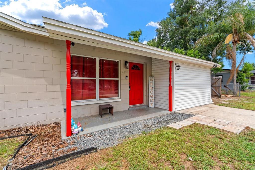 A single-story house exterior features a red front door, red porch columns, and gray siding — 4710 JOYCE DRIVE, LAKELAND, FL
