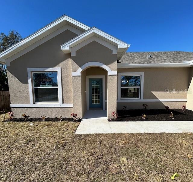 The exterior of a tan, single-story house features a front entrance and two windows — 6163 DAVID BOULEVARD, PORT CHARLOTTE, FL