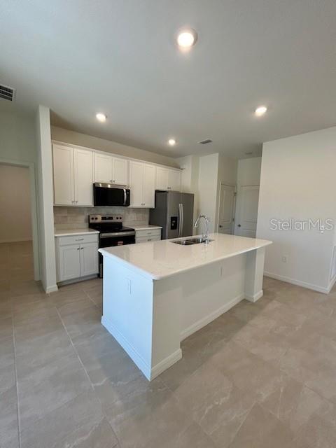 A modern kitchen features white cabinets, a central island with a countertop, and stainless appliances — 6163 DAVID BOULEVARD, PORT CHARLOTTE, FL