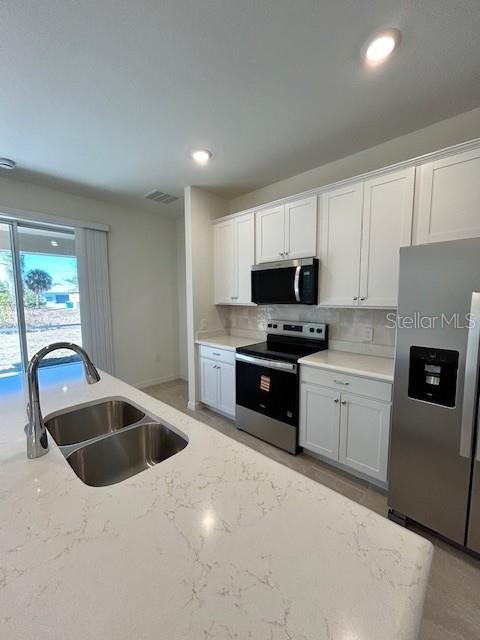 A kitchen features white cabinets, stainless steel appliances, and a large quartz-topped island — 6163 DAVID BOULEVARD, PORT CHARLOTTE, FL