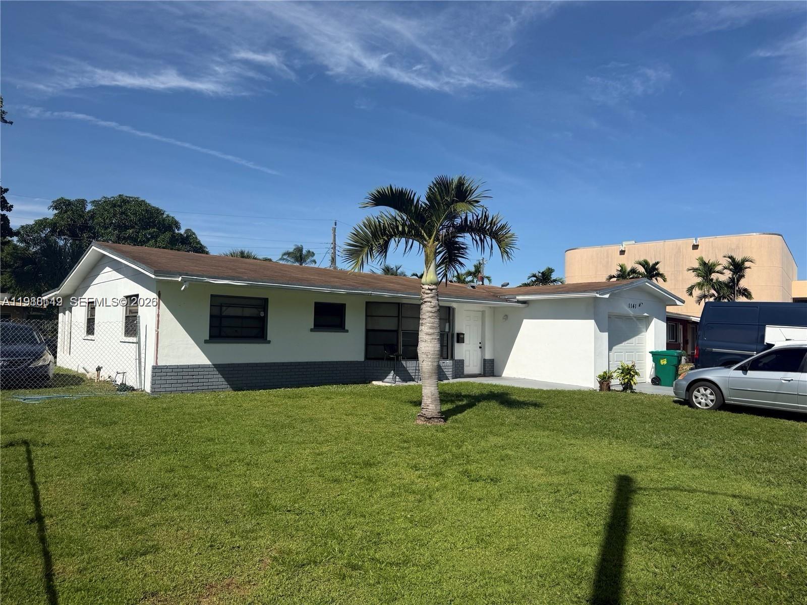 A white single-story house with a gray brick base and a palm tree in front — 1141 NW 41st Ter, Lauderhill FL 33313, LAUDERHILL, FL