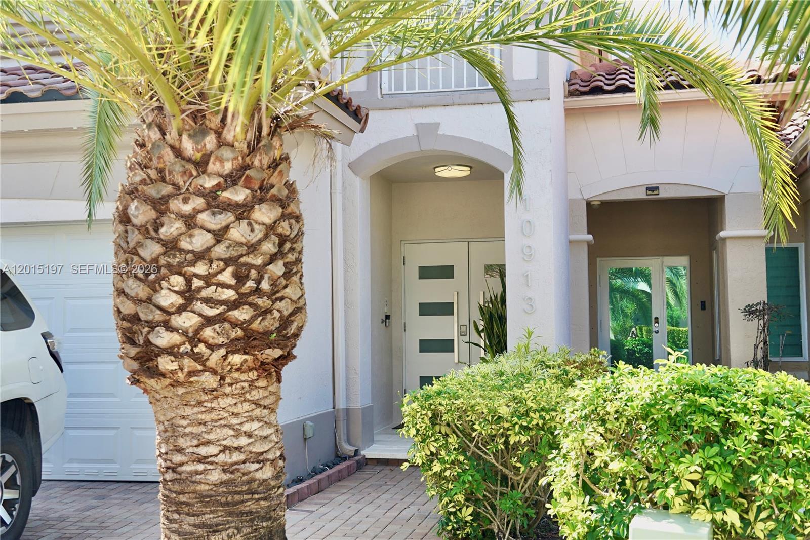 The exterior of a house features a palm tree, a paved walkway, and a front entrance — 10913 NW 67th St, Doral FL 33178, DORAL, FL