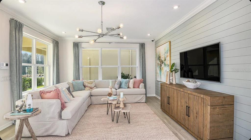 A living room features a sectional sofa, a wood media console, and a shiplap wall — 5156 DOMINION ALLEY, ST CLOUD, FL