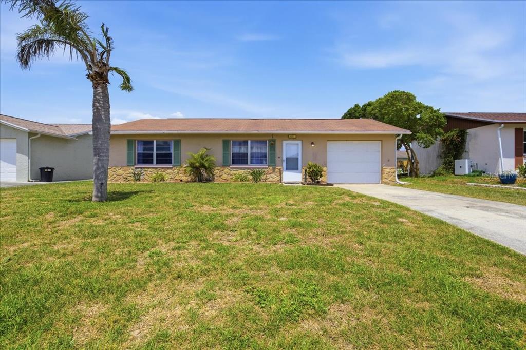A single-story house with a tan exterior, stone accents, and a palm tree in front — 5051 BROOKSIDE LANE, NEW PORT RICHEY, FL
