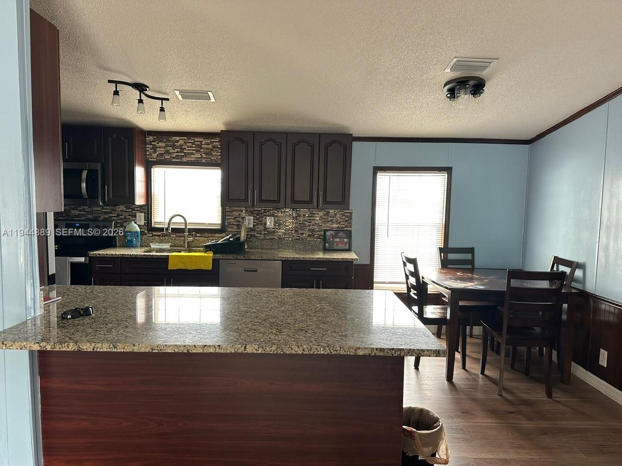 A kitchen with dark wood cabinets, granite countertops, and an adjacent dining area — 1122 JOHNSON RD, Clewiston FL 33440, CLEWISTON, FL