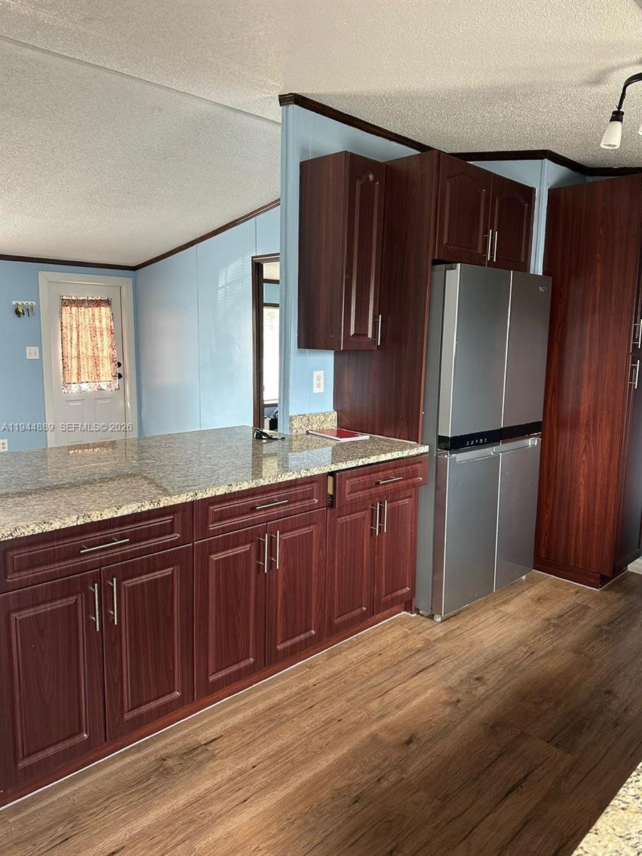 A kitchen features dark wood cabinets, granite countertops, and a stainless steel refrigerator — 1122 JOHNSON RD, Clewiston FL 33440, CLEWISTON, FL