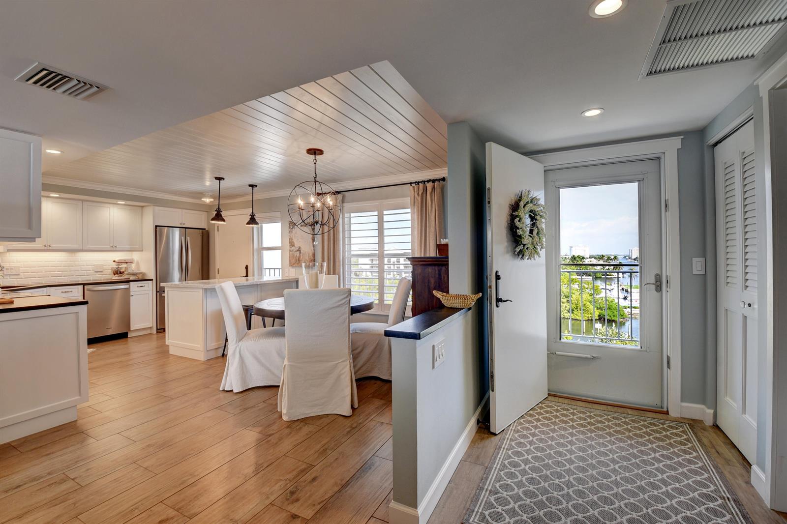 An open-concept kitchen and dining area features white cabinetry, wood-look flooring, and a balcony view — 1 Harbourside Drive # 3702, Delray Beach FL 33483, DELRAY BEACH, FL