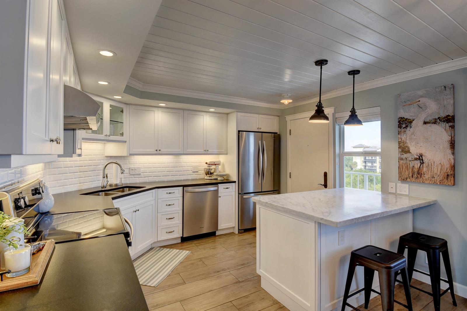A kitchen features white cabinets, a marble-topped island, stainless steel appliances, and wood-look flooring — 1 Harbourside Drive # 3702, Delray Beach FL 33483, DELRAY BEACH, FL