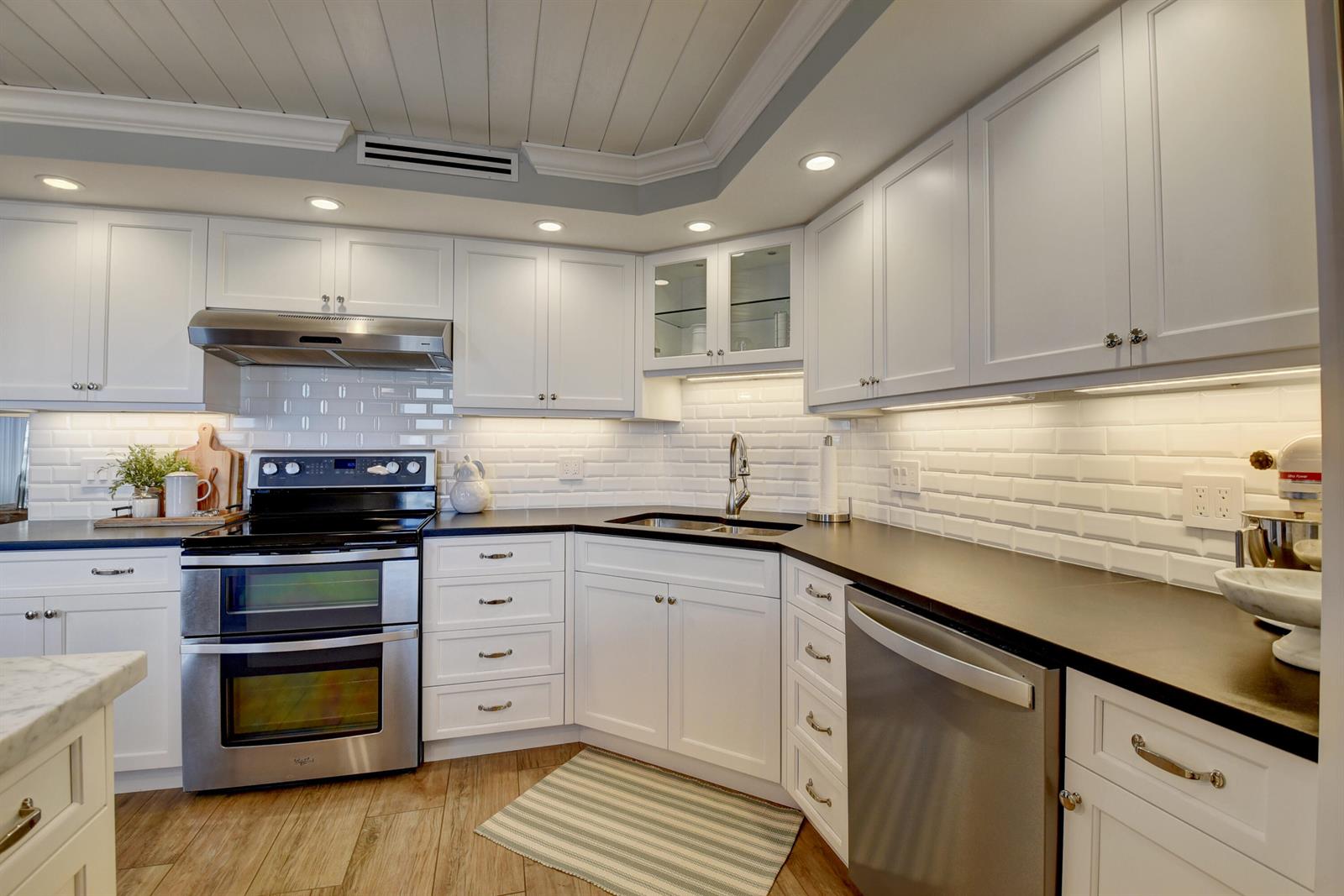 A kitchen with white cabinets, black countertops, stainless steel appliances, and a subway tile backsplash — 1 Harbourside Drive # 3702, Delray Beach FL 33483, DELRAY BEACH, FL