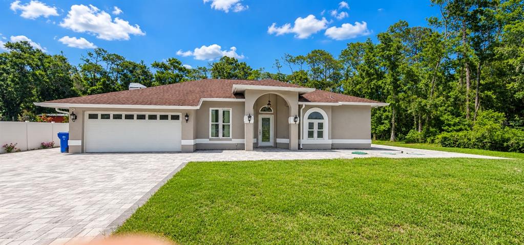 A single-story house with a white garage door, arched entryway, and a paved driveway — 2511 PRISCILLA COURT, LUTZ, FL