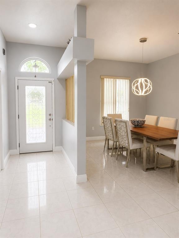 A bright entryway with tile flooring leads into a dining area with a modern chandelier — 2511 PRISCILLA COURT, LUTZ, FL