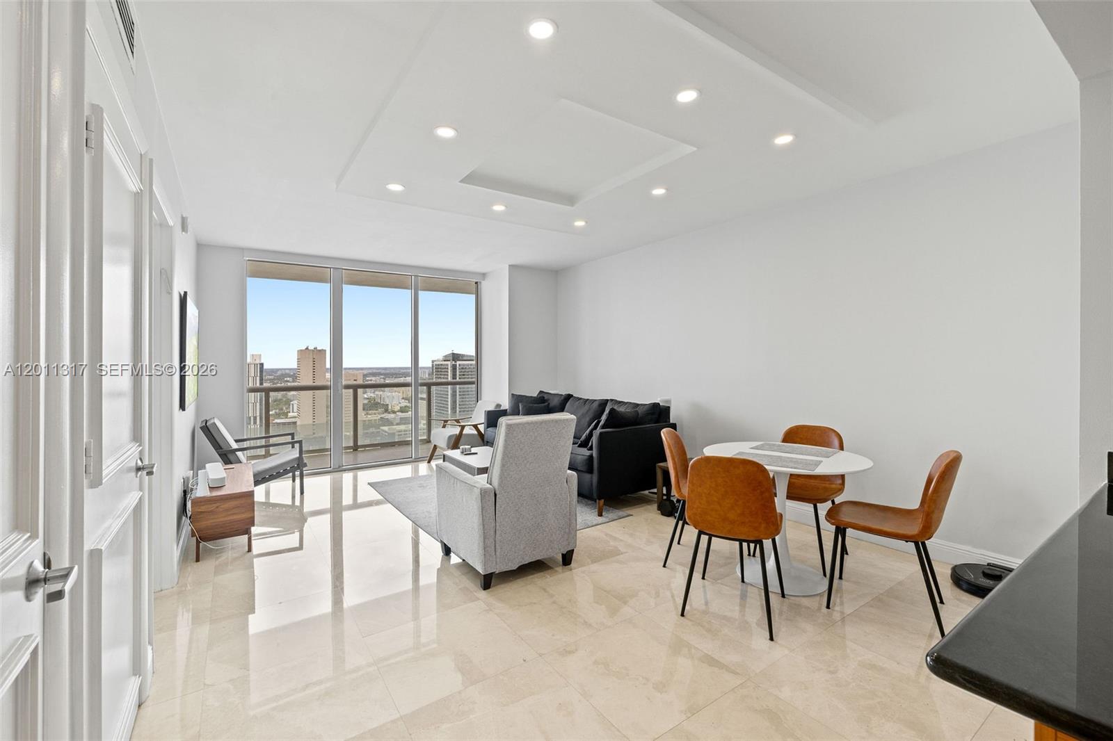 A modern living and dining area features tile floors, recessed lighting, and floor-to-ceiling windows — 50 Biscayne Blvd # 4405, Miami FL 33132, MIAMI, FL