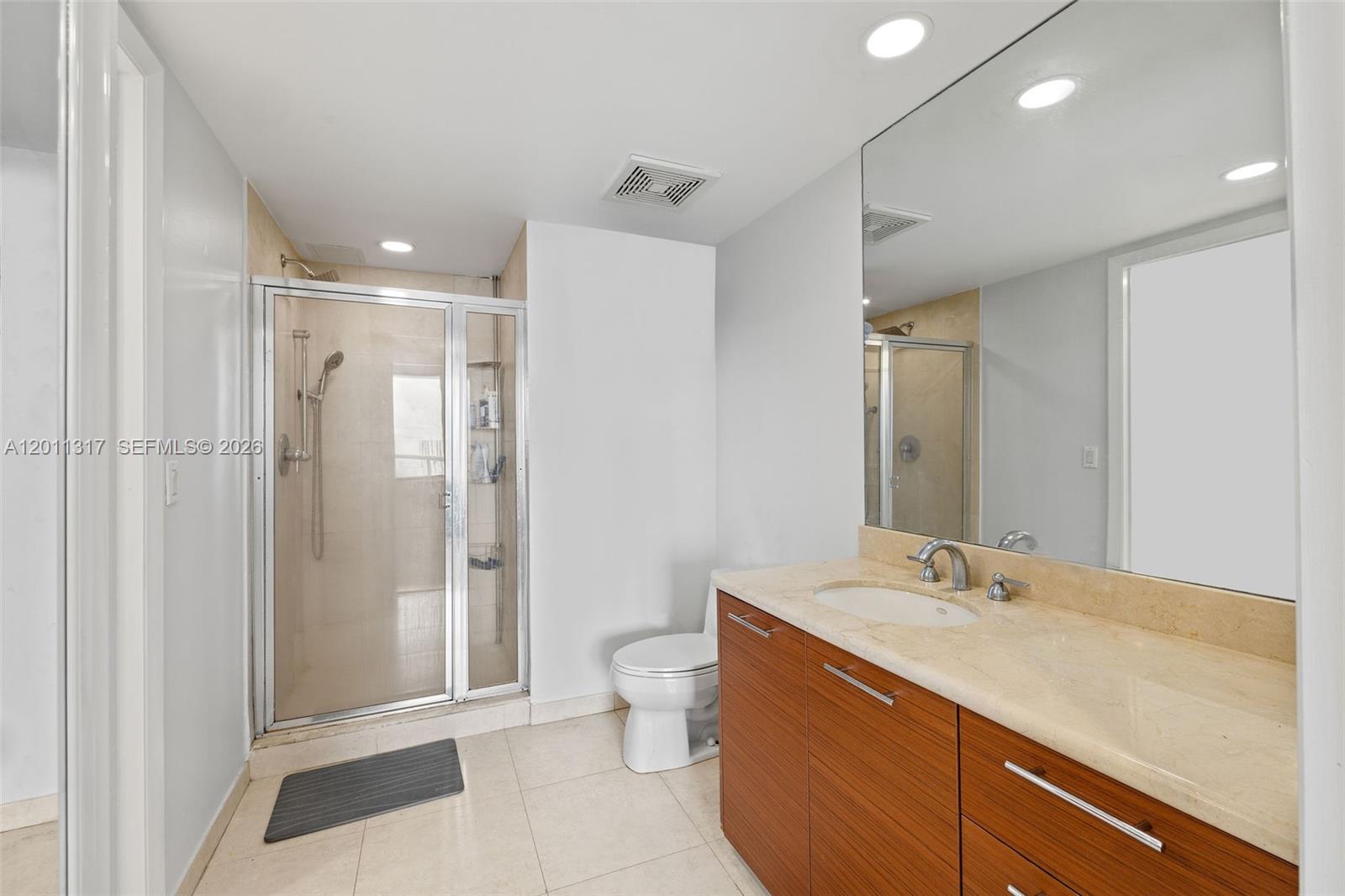 A bathroom features a glass-enclosed shower, a white toilet, and a wood vanity with stone countertop — 50 Biscayne Blvd # 4405, Miami FL 33132, MIAMI, FL