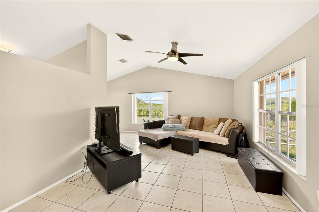 A living room with tile floors, a vaulted ceiling, a ceiling fan, and a sectional sofa — 1400 CLUB DRIVE, TARPON SPRINGS, FL