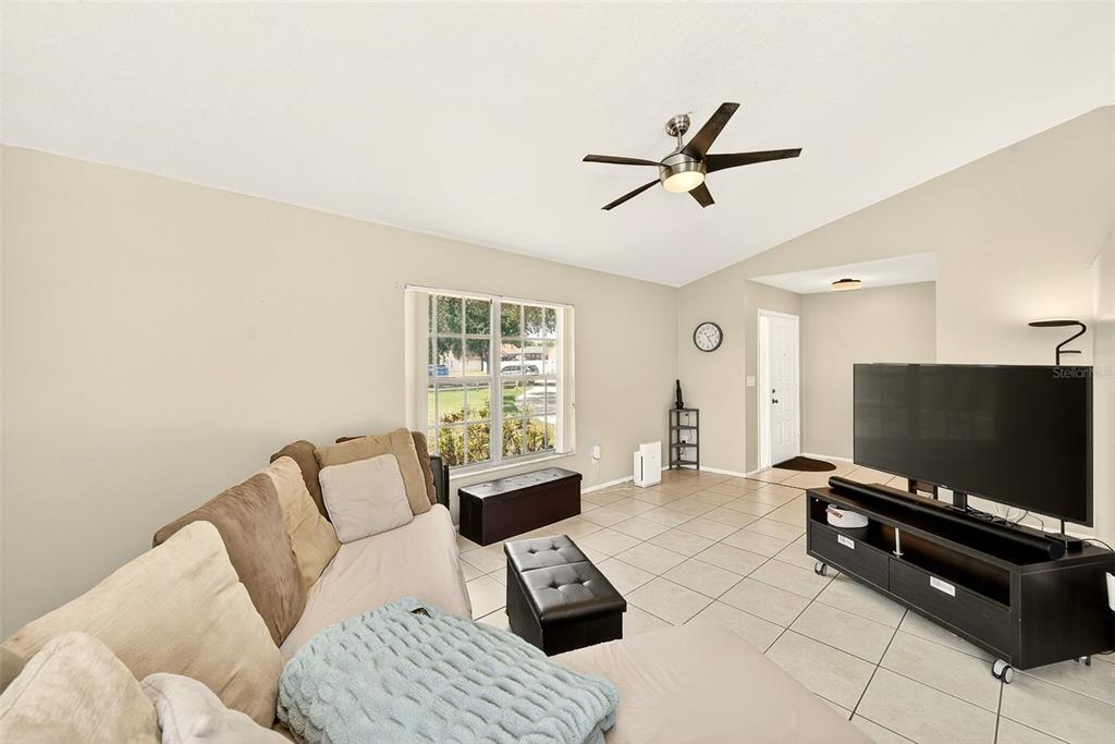 A living room features light tile floors, a ceiling fan, and a large television console — 1400 CLUB DRIVE, TARPON SPRINGS, FL