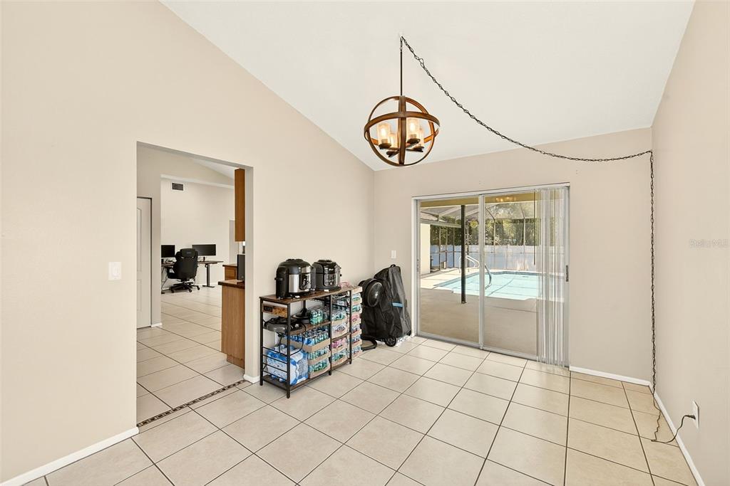 A dining area with tile floors, a hanging orb chandelier, and a sliding glass door — 1400 CLUB DRIVE, TARPON SPRINGS, FL