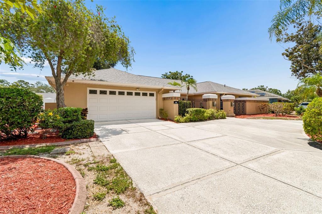 A tan house with a white garage door and a concrete driveway under a blue sky — 1563 MISTY PLATEAU TRAIL, CLEARWATER, FL
