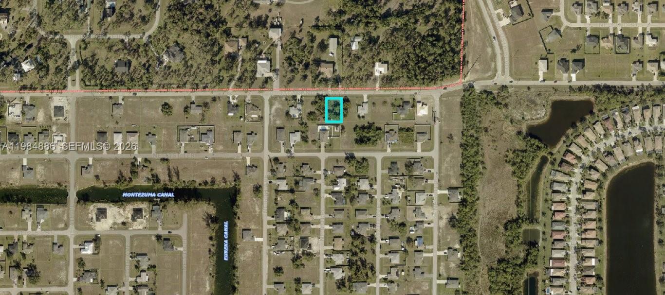 An aerial view shows a vacant rectangular lot bordered by a road and residential houses — 614 Jacaranda Pkwy E, Cape Coral FL 33909, CAPE CORAL, FL