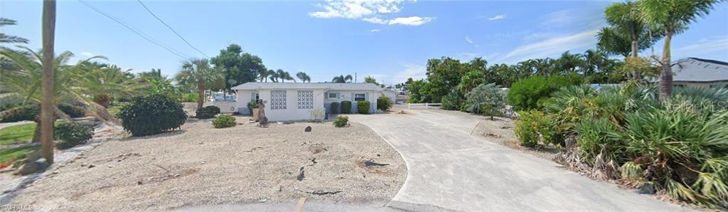 A single-story house with a gravel front yard and a concrete driveway under a blue sky — 3435 SEA HOLLY LANE, ST JAMES CITY, FL