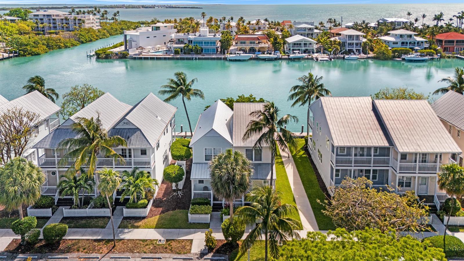 An aerial view shows three houses with metal roofs situated along a canal in Florida — 7051 Harbor Village Drive, FL 33050, FL