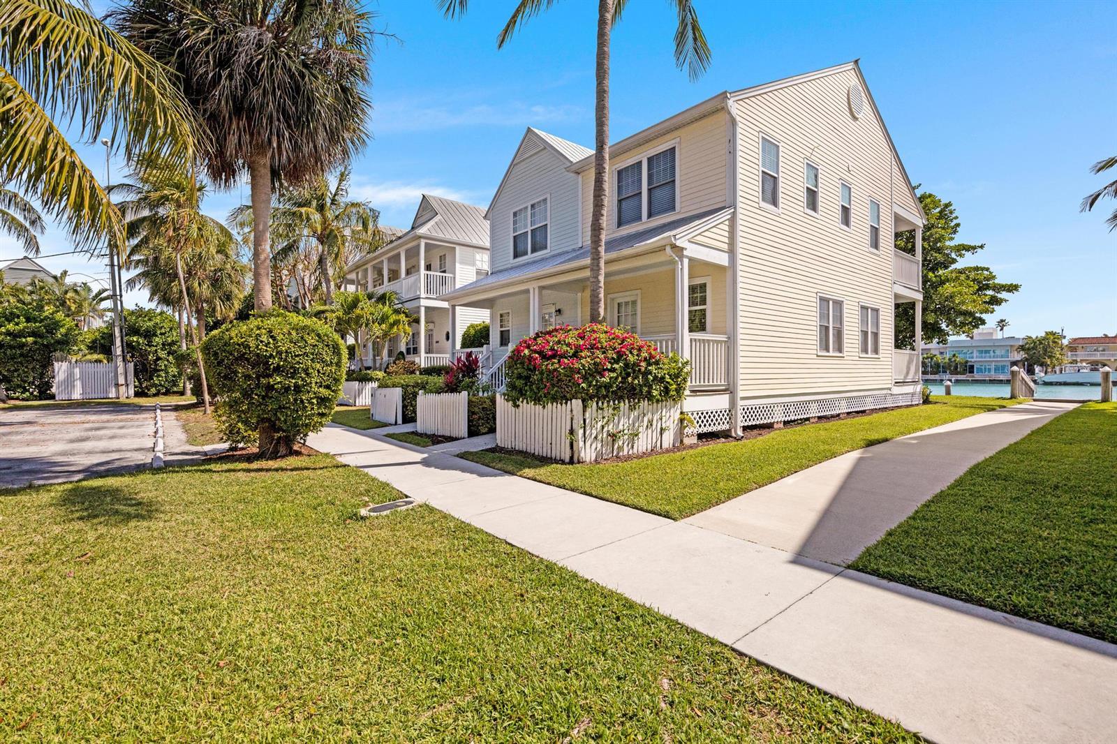 A light yellow two-story house with a white picket fence and a sidewalk — 7051 Harbor Village Drive, FL 33050, FL
