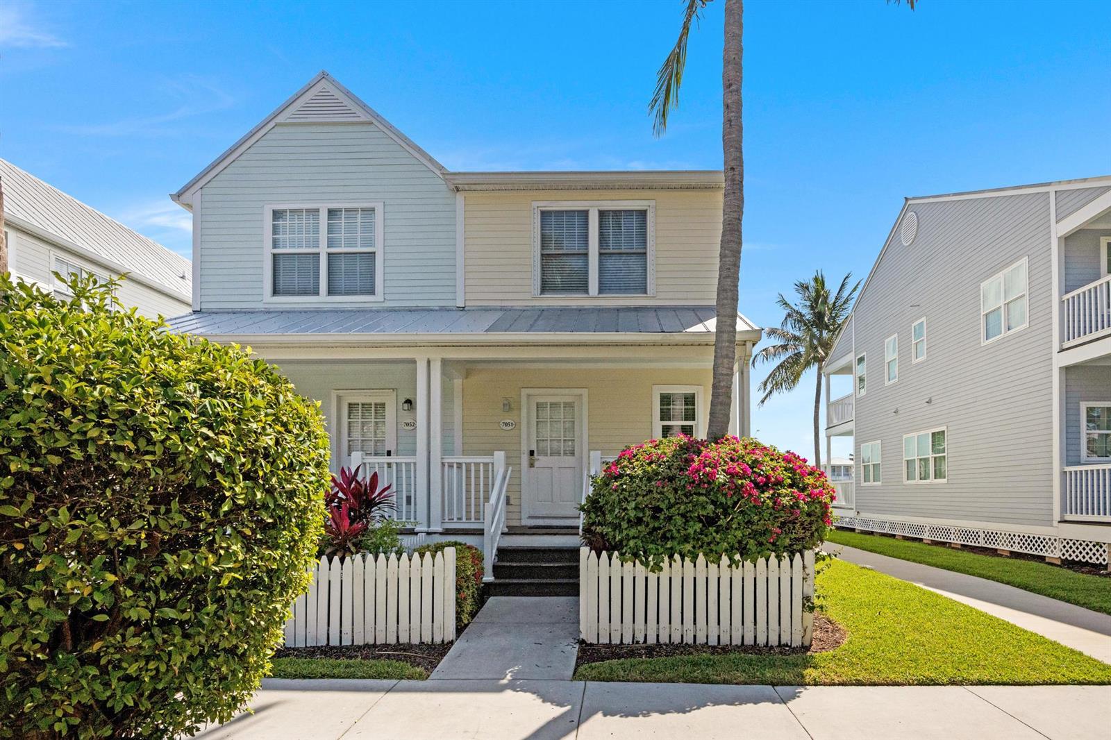 A two-story duplex with pastel siding, a front porch, and a white picket fence — 7051 Harbor Village Drive, FL 33050, FL