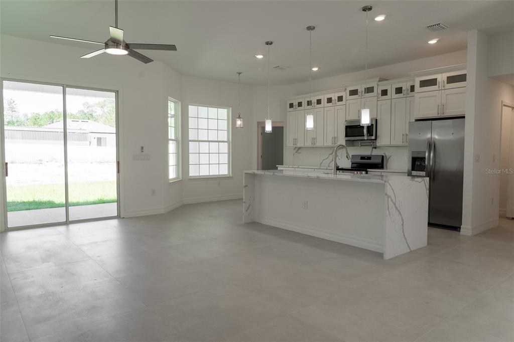 A modern kitchen features white cabinetry, a marble-topped island, and tile flooring — 16559 SW 48TH TERRACE, OCALA, FL