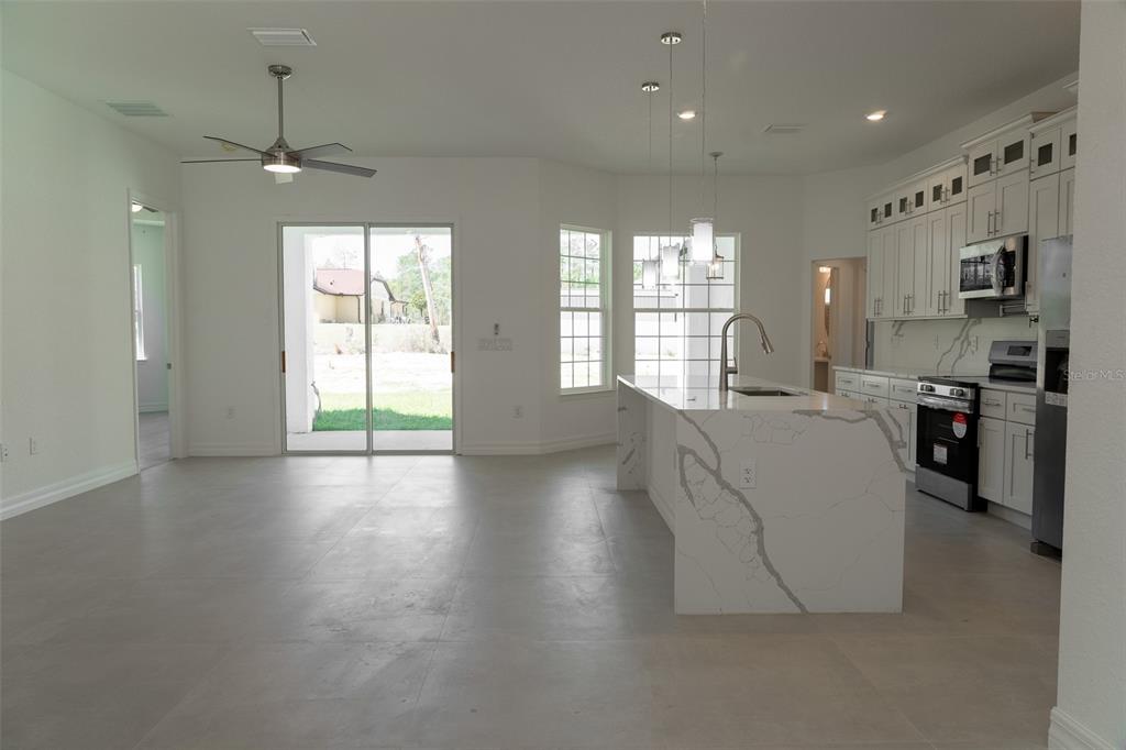 An open-concept kitchen and living area features white cabinetry, a marble-topped island, and tile flooring — 16559 SW 48TH TERRACE, OCALA, FL
