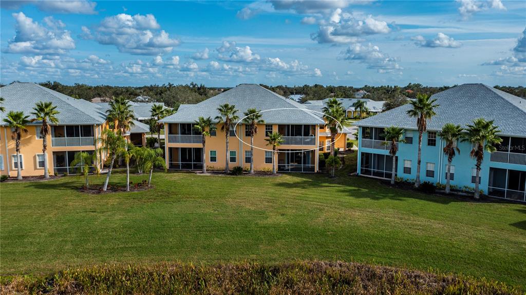 An exterior view of a multi-story apartment building with screened balconies and palm trees — 25601 HERITAGE LAKE BOULEVARD UNIT 46, PUNTA GORDA, FL