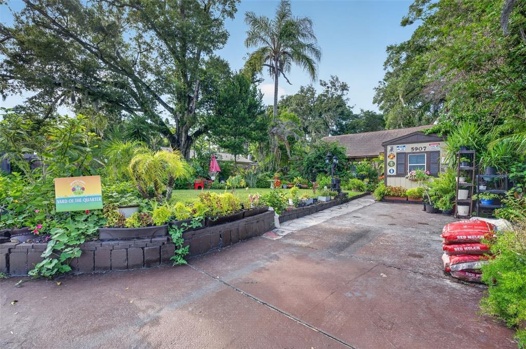 A paved driveway leads to a house exterior with a landscaped garden and retaining wall — 5907 UONA AVENUE, ORLANDO, FL