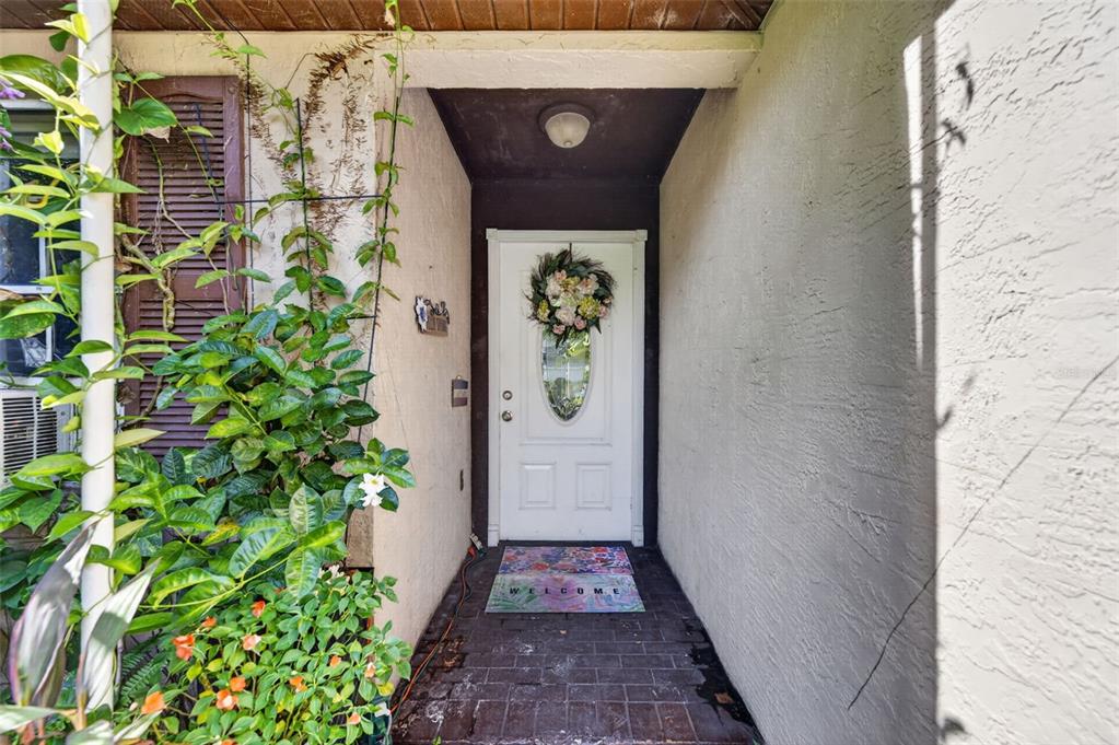 A white front door with a floral wreath sits at the end of a brick entryway — 5907 UONA AVENUE, ORLANDO, FL