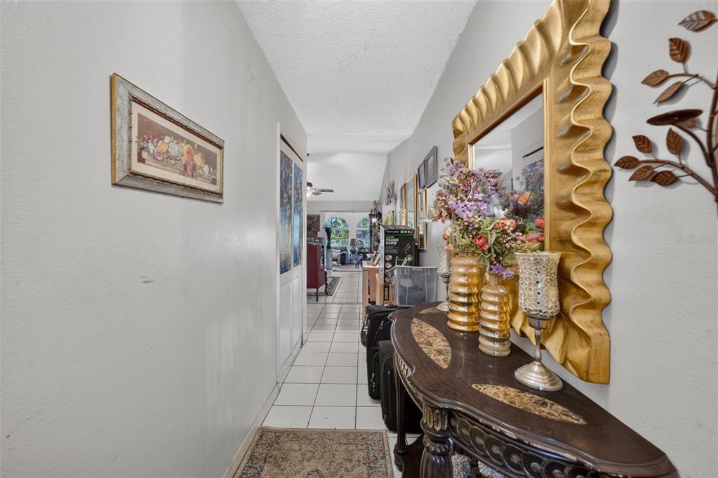 A hallway features a console table with a mirror, floral decor, and tile flooring — 5907 UONA AVENUE, ORLANDO, FL
