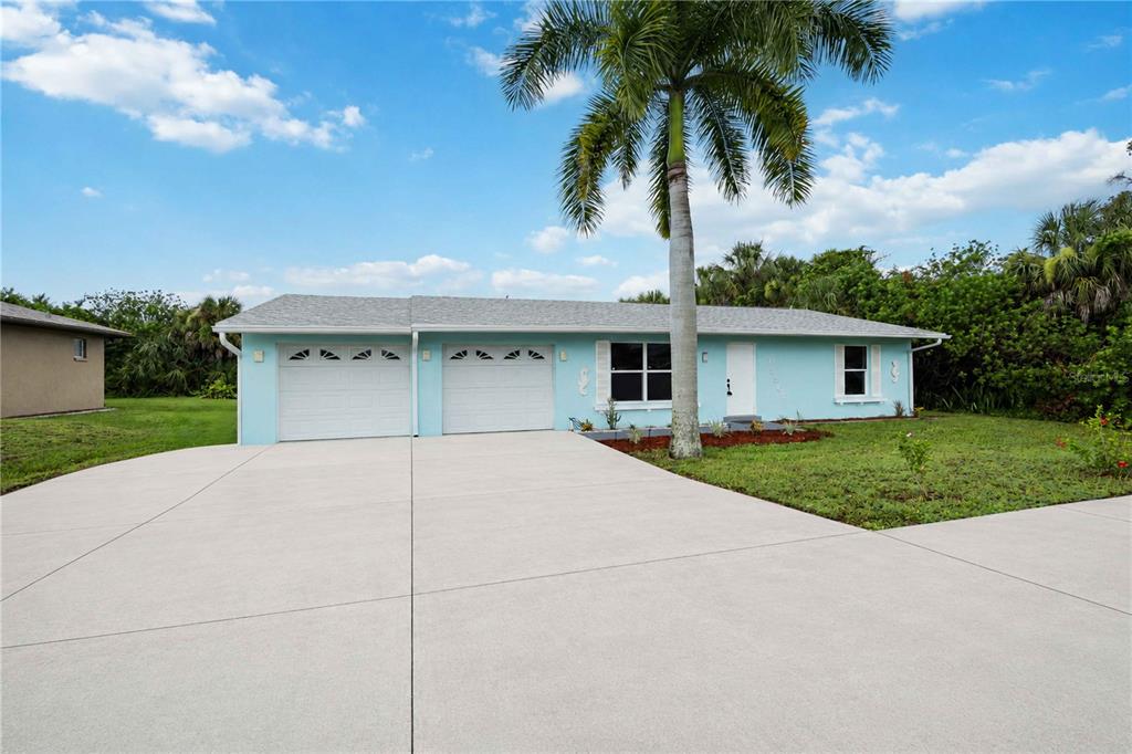 A light blue single-story house with a two-car garage and a large palm tree — 19367 EDGEWATER DRIVE, PORT CHARLOTTE, FL