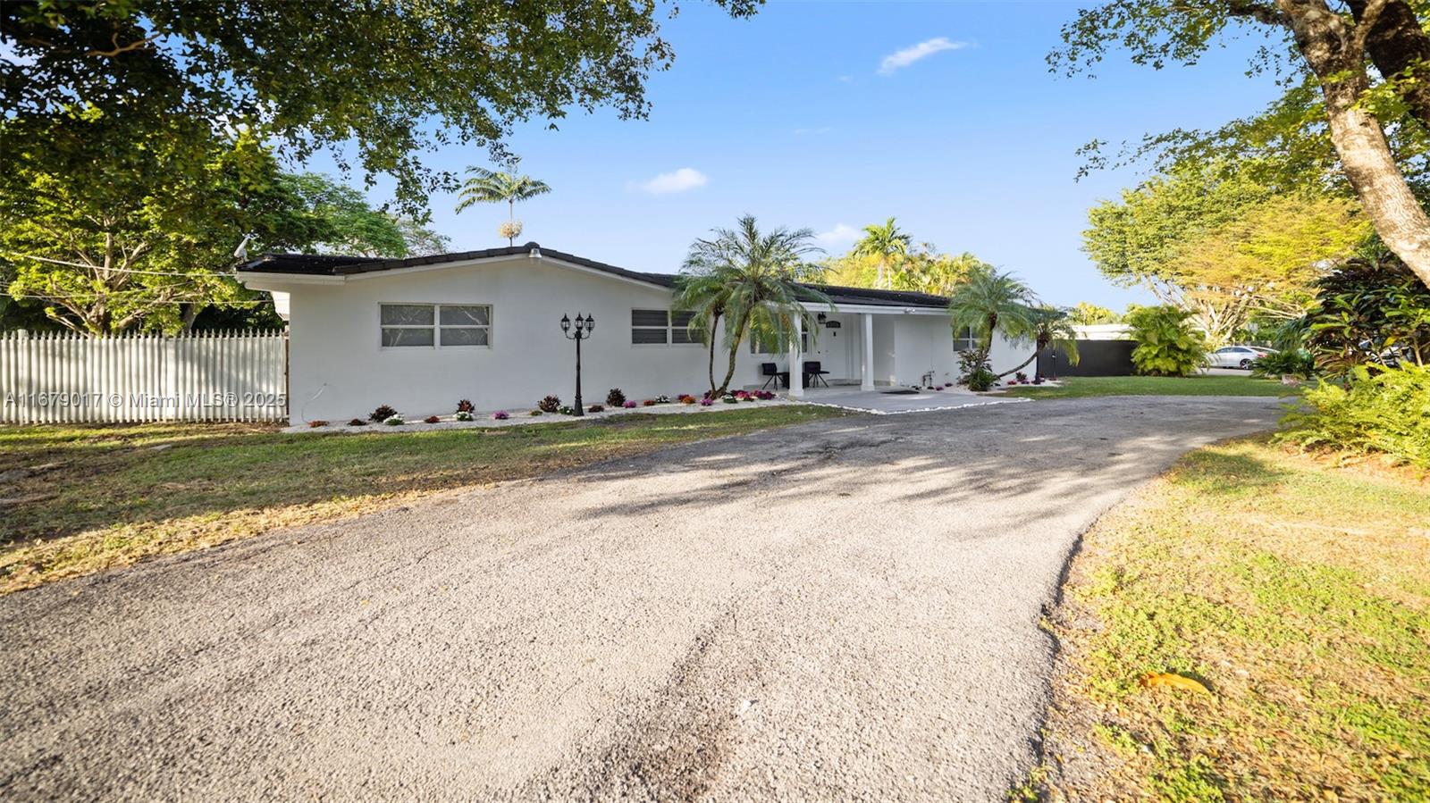 A single-story white house with a gravel driveway and palm trees in the front yard — 13550 SW 99th Pl, Miami FL 33176, MIAMI, FL