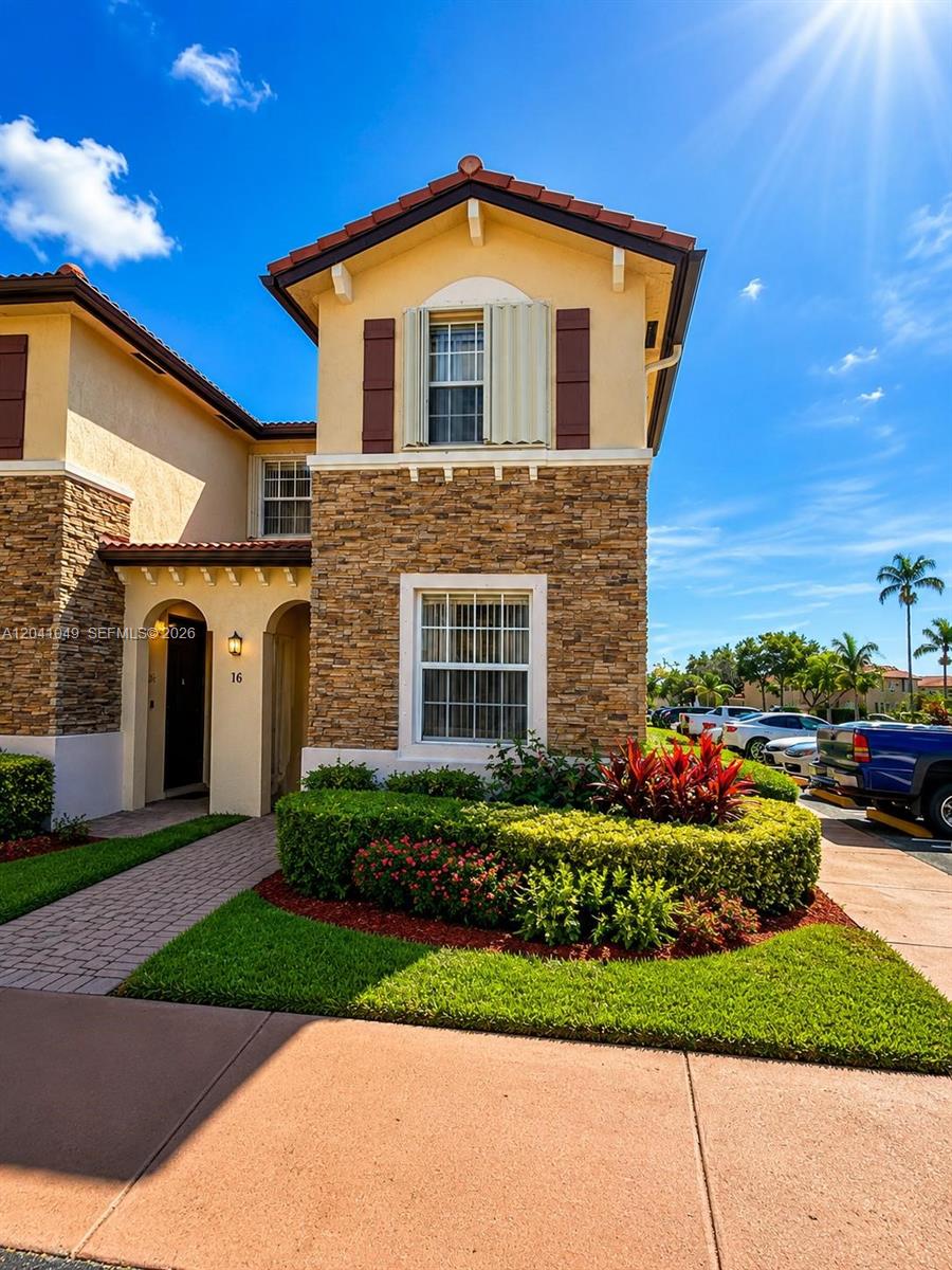 A two-story townhouse exterior features stone veneer, stucco walls, and a tiled roof — HOMESTEAD, FL