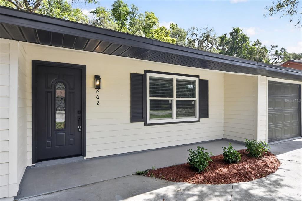 The exterior of a house features a dark front door, a window with shutters, and a garage — 262 MARJORIE BOULEVARD, LONGWOOD, FL
