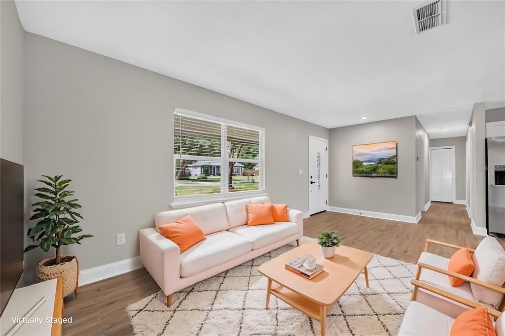 A living room features a light pink sofa, a wooden coffee table, and wood-look flooring — 262 MARJORIE BOULEVARD, LONGWOOD, FL
