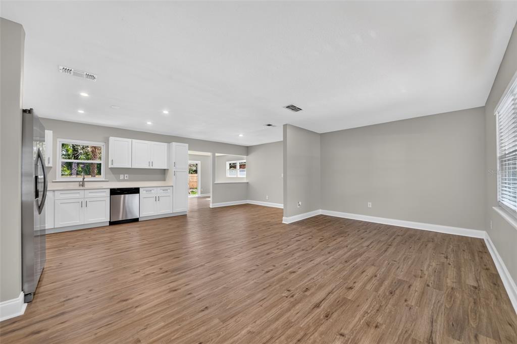 A kitchen with white cabinets and stainless appliances opens into a spacious, light-filled living area — 262 MARJORIE BOULEVARD, LONGWOOD, FL