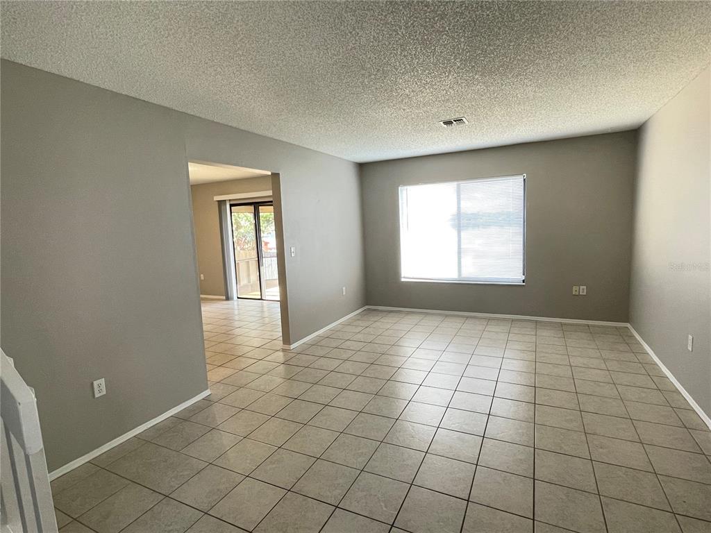 A living room with light-colored tile flooring, gray walls, and a large window — 687 LAKE DEXTER CIRCLE, WINTER HAVEN, FL