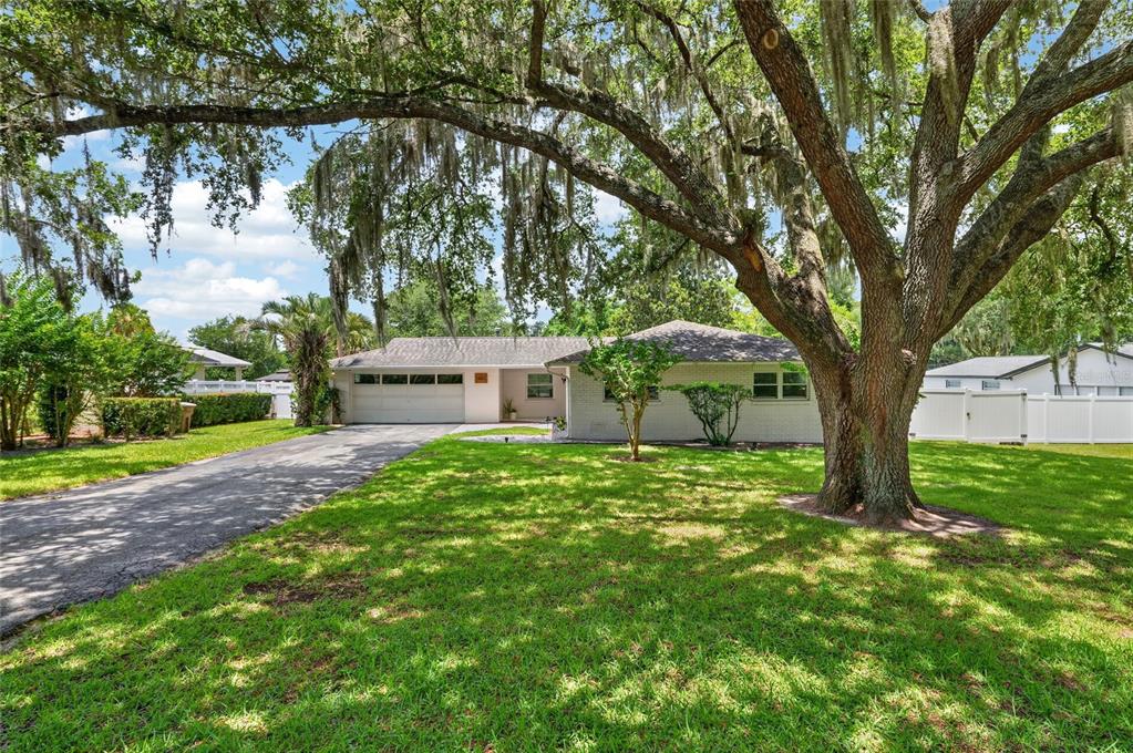 A single-story house with a white brick exterior, a two-car garage, and a large oak tree — 1502 SE 16TH AVENUE, OCALA, FL