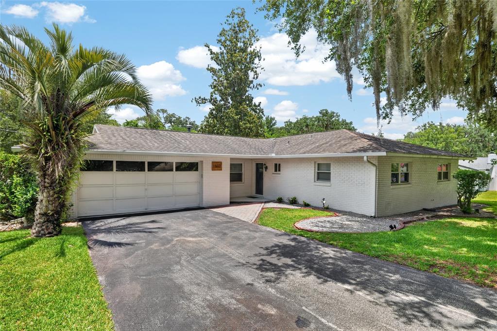 A single-story white brick house with a two-car garage and a paved driveway — 1502 SE 16TH AVENUE, OCALA, FL