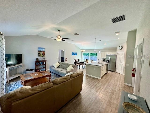 An open-concept living room and kitchen feature light wood flooring and vaulted ceilings — 5423 NW 52ND AVENUE, OCALA, FL