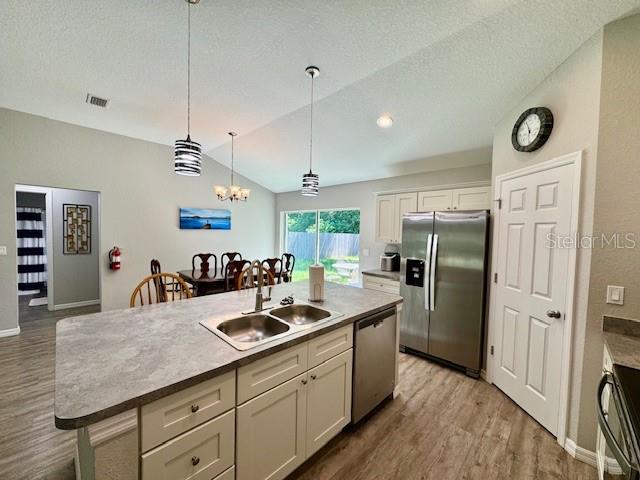 A kitchen features a central island with a sink, stainless steel appliances, and light cabinetry — 5423 NW 52ND AVENUE, OCALA, FL