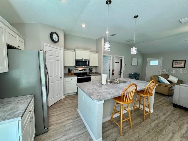A kitchen features a gray island with two wooden stools and light-colored cabinetry — 5423 NW 52ND AVENUE, OCALA, FL