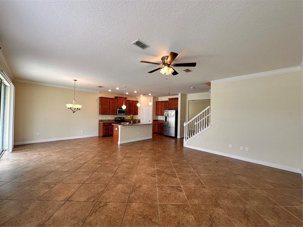 A spacious open-concept kitchen and living area with tile floors, wooden cabinets, and a staircase — 7409 FAIRGROVE AVENUE, WINDERMERE, FL