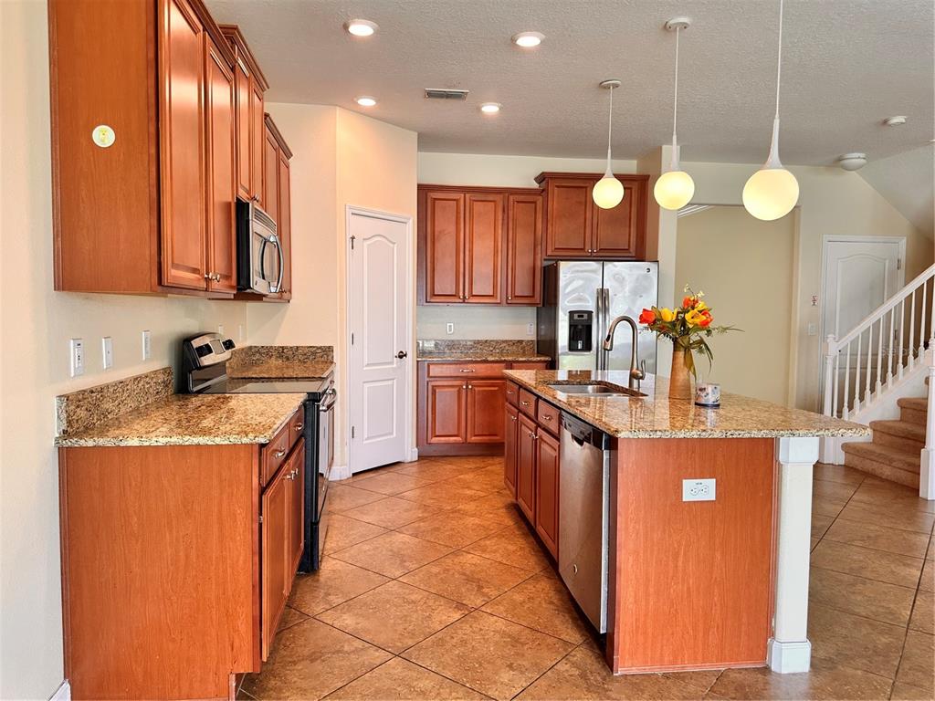 A kitchen with wood cabinets, granite countertops, tile flooring, and a central island — 7409 FAIRGROVE AVENUE, WINDERMERE, FL